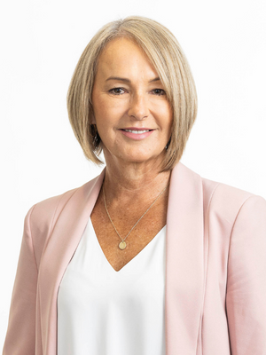 Portrait of a blonde woman with short hair wearing a white top and pink jacket