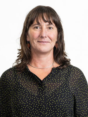 Portrait of a women with long dark hair and a fringe wearing a black spotted top