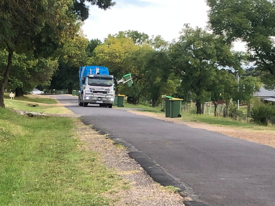 Rubbish collection truck coming down a street