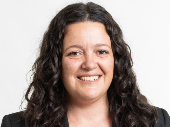 Portrait of woman with dark curly hair smiling directly at camera